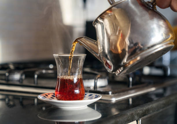 Turkish Tea Teapot filling a glass of Turkish tea on kitchen desk. black tea stock pictures, royalty-free photos & images