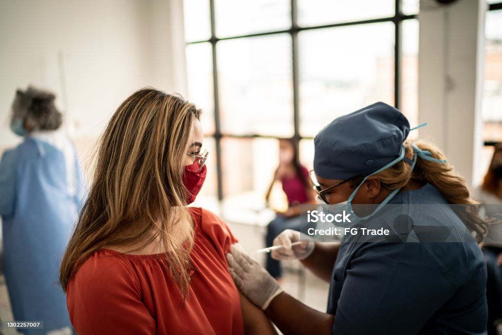 Teenager girl being vaccinated - wearing face mask Vaccination Stock Photo