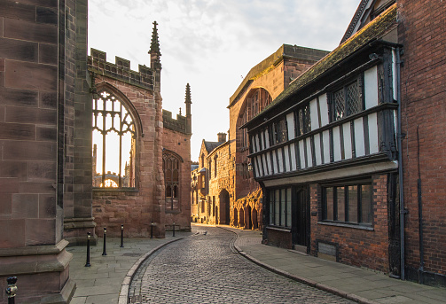 Bailey Lane showing the old cathedral ruins on the left and Coventry guildhall and a Tudor house on the right. The road leads to Coventry university.