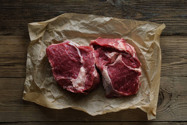 istock Raw meat on wooden board with dark background 1302260135