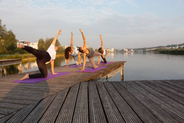 istock yoga class exercising on jetty at urban lake during sunrise 1302261299