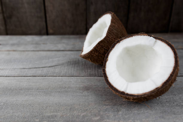 istock Broken coconuts on gray wooden background. White coconut pulp 1302261311