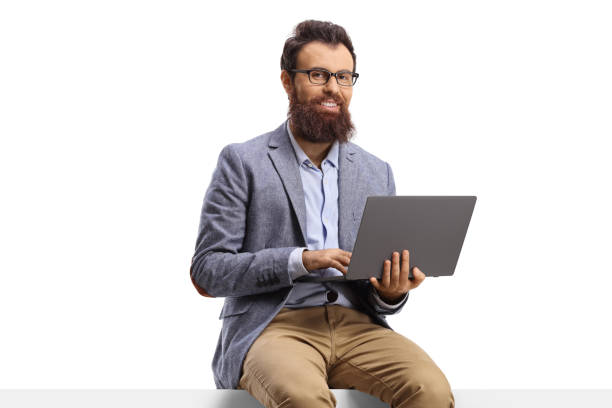 istock Bearded man seated on a blank panel with a laptop 1302263775