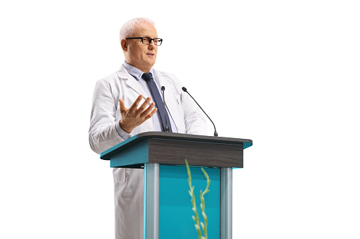 Mature doctor giving a speech at a conference isolated on white background