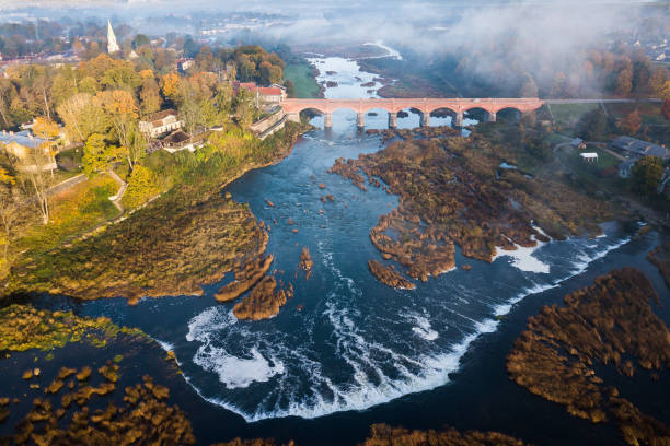 cachoeira venta rapid, a cachoeira mais larga da europa e ponte de tijolos longas, kuldiga, letônia. - letónia - fotografias e filmes do acervo