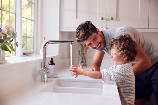 padre ayudando a su hijo a lavarse las manos con jabón en casa para detener la propagación de la infección en la pandemia de salud - sink fotografías e imágenes de stock