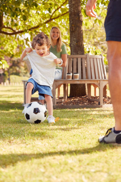 Family With Young Son Having Fun In Park Playing Football And Sitting On Seat Under Tree Family With Young Son Having Fun In Park Playing Football And Sitting On Seat Under Tree 3 6 months stock pictures, royalty-free photos & images