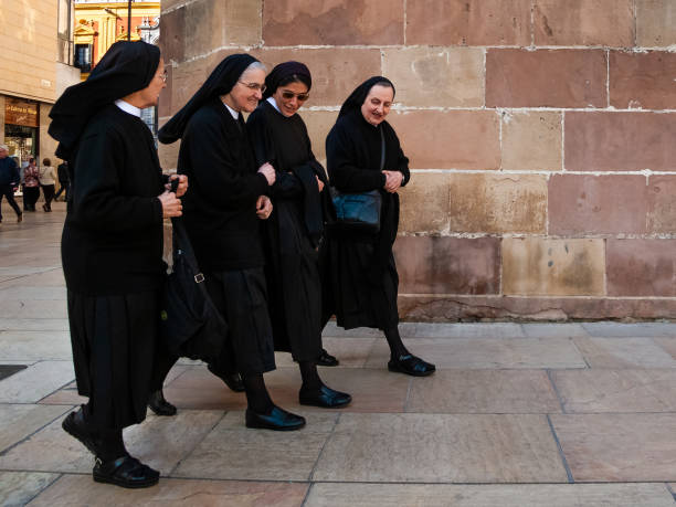 23.02.20. Malaga, Spain. Four nuns walking on the street talking and smiling with black dresses stock photo