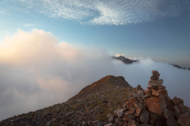 istock cairn on top of a mountain surrounded by clouds 1302268628