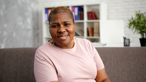 Obese African-American mature lady with short hair looks straight and smile closeup