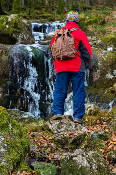 istock Man stops to look at frozen waterfall 1302270946