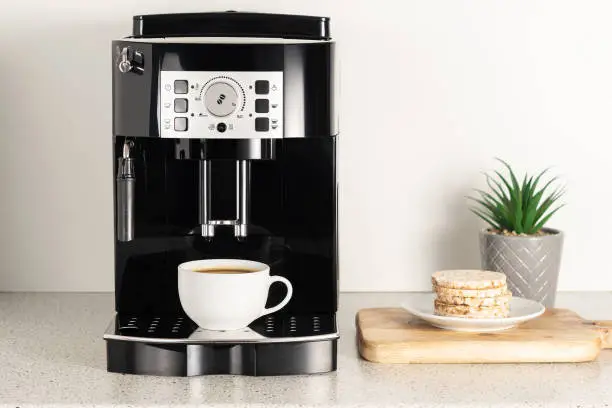 Photo of Modern espresso coffee machine with a cup in interior of kitchen closeup.