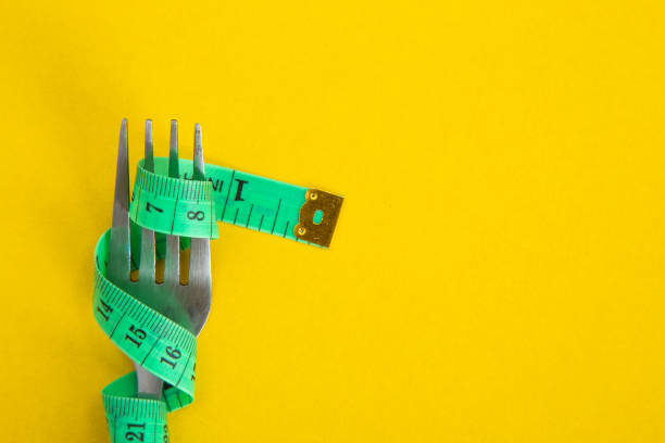 istock Proper nutrition for slimming. Fork with wound measuring tape. Diet Concept 1302272486