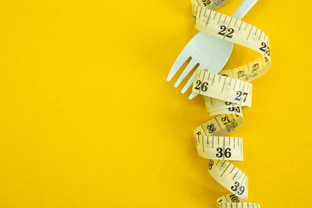 istock Proper nutrition for slimming. Fork with wound measuring tape. Diet Concept 1302272525