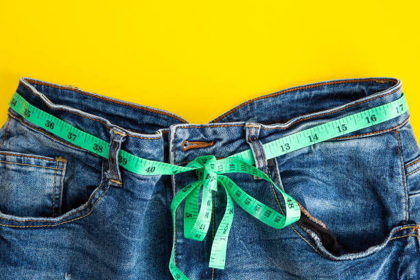 istock jeans with meter belt slimming on the yellow background. Diet ans slimming concept 1302272641