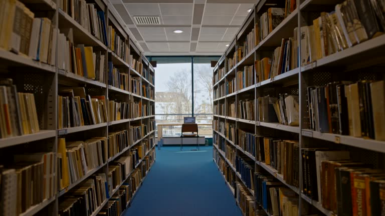 SLO MO Laptop on a table at the end of an aisle of books in a library