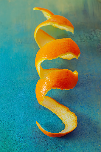 Blue green background with a peel of tangerine. Close-up spiral of citrus orange, concept for healthy food. Top view. Soft focus. Shallow depth of field.