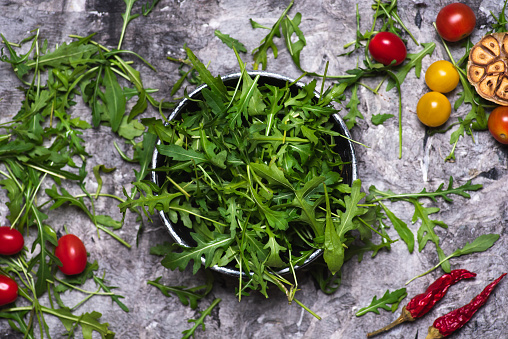 Arugula or ruccola salad plant with food ingredients tabletop view