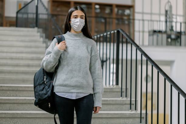 istock Female student with protective face mask and backpack in university 1302278833