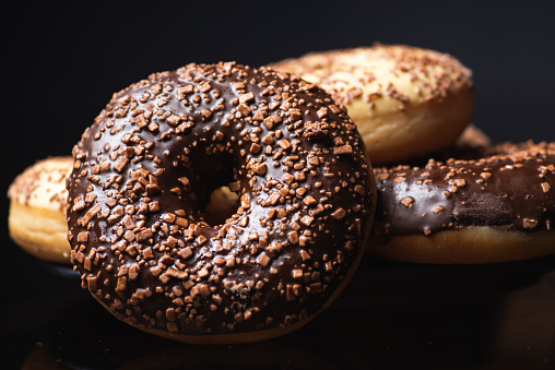 Sweet donuts with chocolate sprinkles dessert on dark background closeup