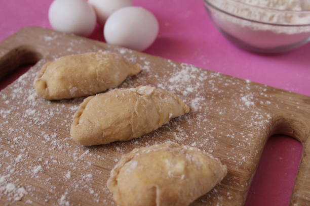 istock Raw cooking dumplings lie on a board beside egg flour on a pink background view from above 1302280923