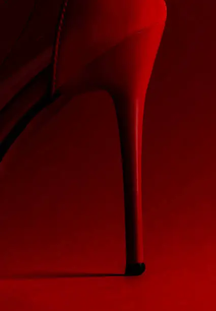 Close-up of red high heel against red background.