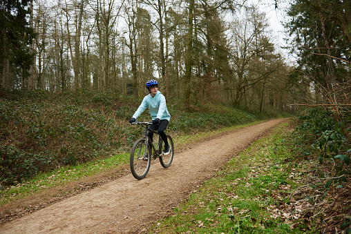 A mountain bike cyclist riding down hill along a woodland cycle trail.