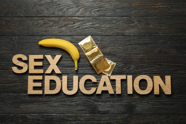 mots éducation sexuelle, banane et condoms sur le fond en bois - condom sex education contraceptive aids photos et images de collection