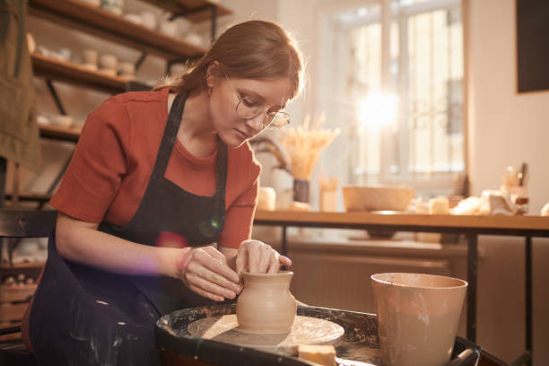 太陽の光の中の若い女性の陶芸家 - potter small business pottery happiness ストックフォトと画像