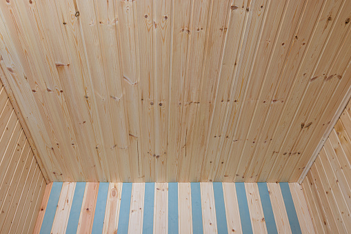 Part of the ceiling and walls finished with wooden lining in a small country room