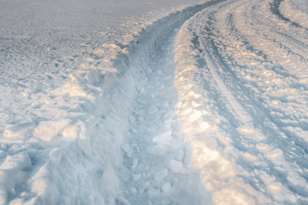 Dirt road covered with fresh snow with tire tracks.