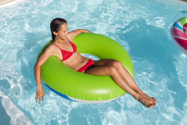 istock Mixed race woman having fun playing on inflatable in swimming pool 1302290768