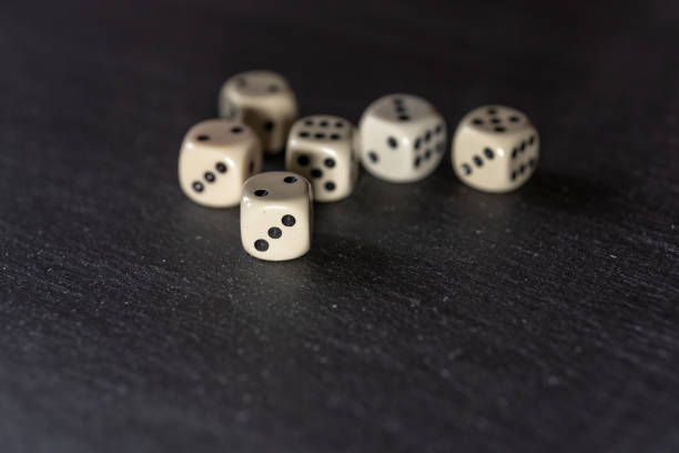 istock Six dice lie on a neutral, dark stone slab. 1302291083