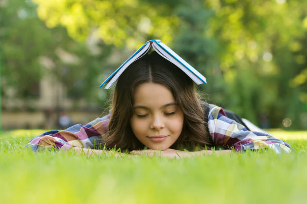 Calming book. Small child sleep on green grass. Bibliotherapy. Mindfulness and relaxation. Napping time. Back to school. Non-formal education and learning. Relaxing book for better sleep Calming book. Small child sleep on green grass. Bibliotherapy. Mindfulness and relaxation. Napping time. Back to school. Non-formal education and learning. Relaxing book for better sleep. mindfulness children stock pictures, royalty-free photos & images