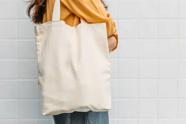 Photo of Woman is holding tote bag canvas fabric for mockup blank template.