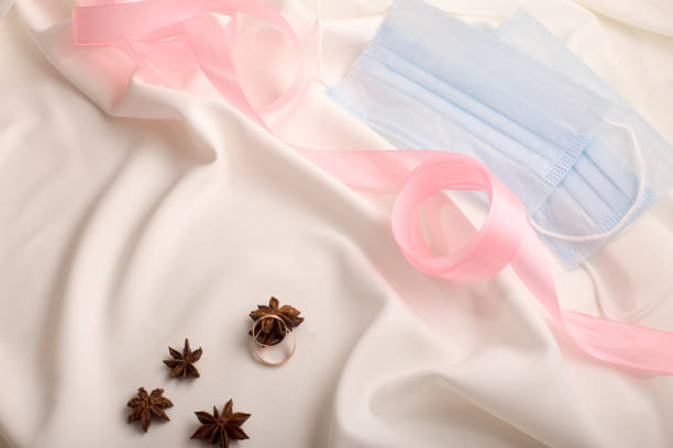 wedding rings on a white dress with pink tape and stars anise stock photo