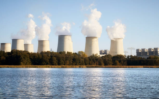 istock Power plant with smoking chimneys by a lake at sunset. 1302302280
