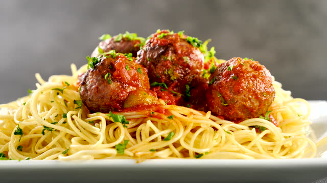 spaghetti with meatball and pouring parsley