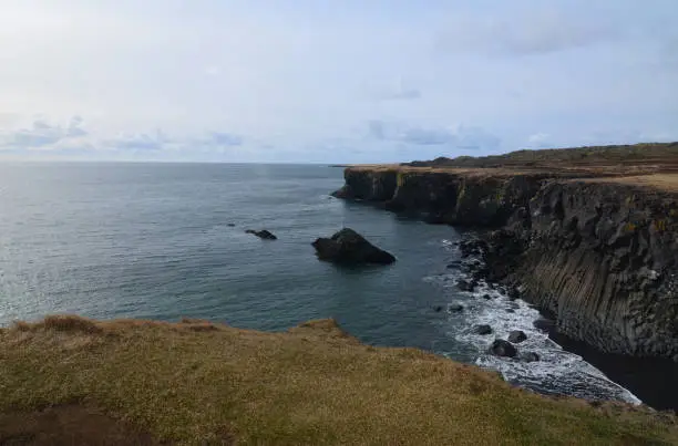 Seascape with fantastic basalt column cliffs made of rock on the coast.