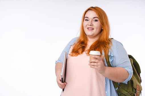 Estudiante de mujer regordeta segura con una taza de café aislada sobre fondo blanco photo