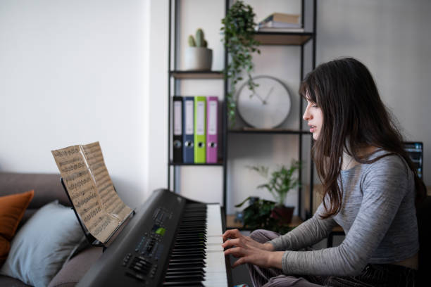 музыкантка, играющая на пианино дома во время карантина. - электропиано стоковые фото и изображения