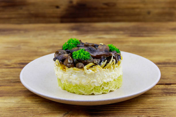 tasty layered salad with roasted mushrooms, potato, eggs, cheese and mayonnaise on wooden table - 5898 imagens e fotografias de stock