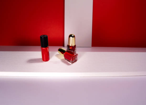 istock Red lipstick and nail polish on white table and bright geometric background 1302308759