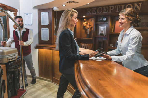 Woman paying with her credit card in the hotel Business woman making mobile payment at the hotel bellhop stock pictures, royalty-free photos & images