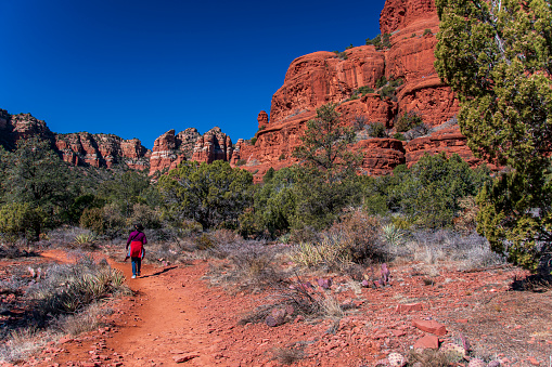A senior woman hiking on the trails that lead through the red rock country of Sedona, Arizona. She is admiring the sandstone formations.