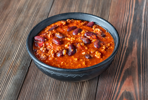 Bowl of chili con carne on a wooden table