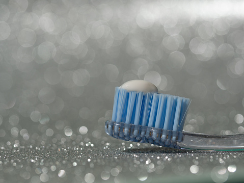 toothbrush with recommended size of toothpaste equivalent to the size of a pea on a shiny gray background. horizontal stock photo with copyspace