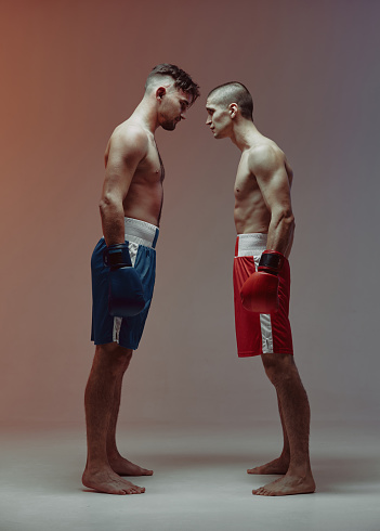 Athletic guys boxers with fit bare torsos standing in stance face to face before fight workout, martial arts concept. High quality photo