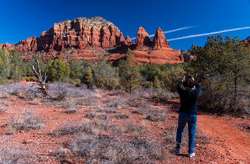 A senior woman photographing the red rock formations of Sedona, Arizona.