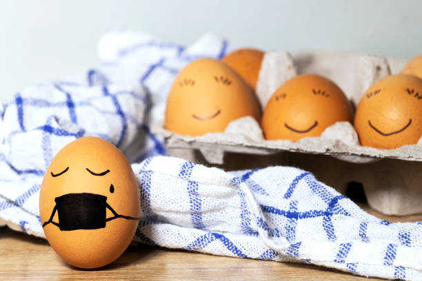 istock Creative Easter eggs with Corona virus protection, egg in a black mask in a quarantine. Diverse chicken eggs with smile on grey background. Flat lay, top view, mockup, copy space. 1302317182